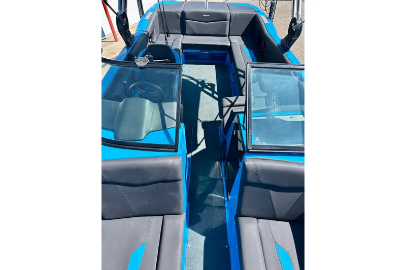 Slide: The Image of 2021 MasterCraft NXT24 boat interior with blue and gray seating, steering wheel, and windshield. - 50