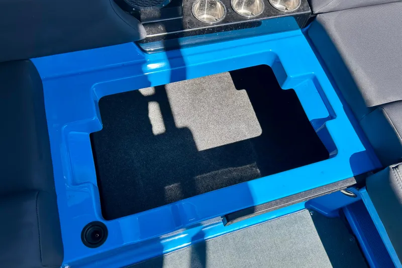 Slide: The Image of 2021 MasterCraft NXT24 boat interior storage compartment with blue trim and cup holders. - 58