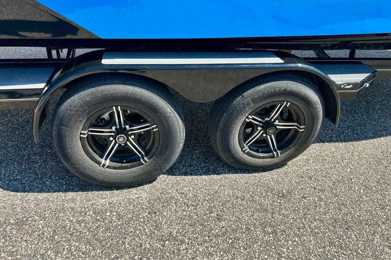 Slide: The Image of 2021 MasterCraft NXT24 trailer wheels on asphalt, featuring black rims and tires. - 66