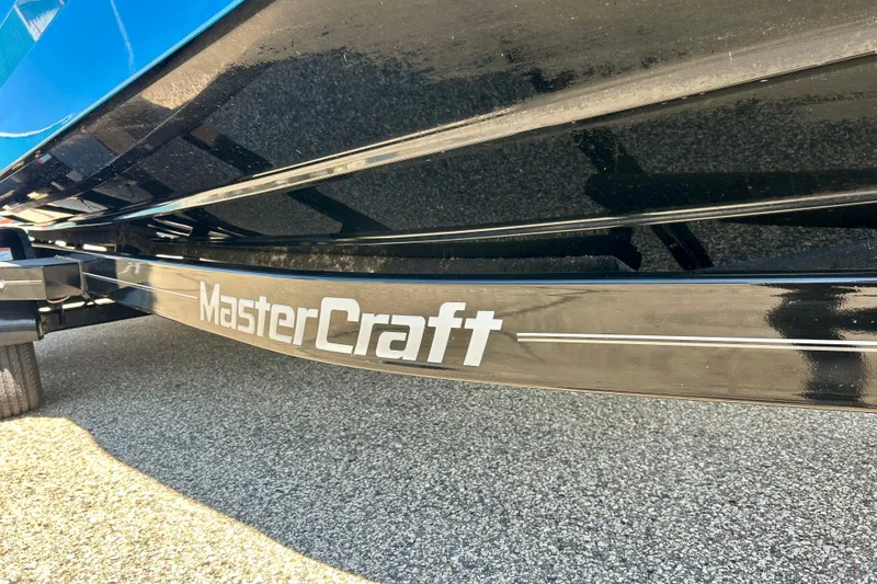 Slide: The Image of 2021 MasterCraft NXT24 boat trailer with logo, parked on gravel surface. - 74