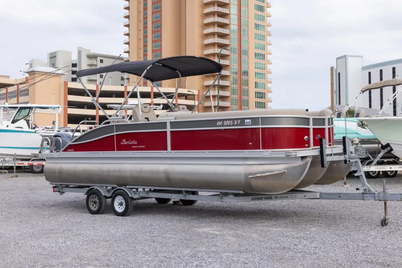 The Image of 2021 Barletta C24UC pontoon boat on trailer, parked near tall buildings. - 0