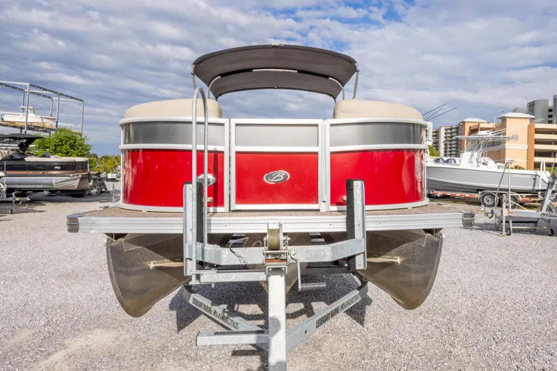 Slide: The Image of 2021 Barletta C24UC pontoon boat on trailer, red exterior, parked outdoors. - 18