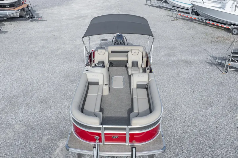 Slide: The Image of 2021 Barletta C24UC pontoon boat with spacious seating and canopy, parked on gravel. - 19