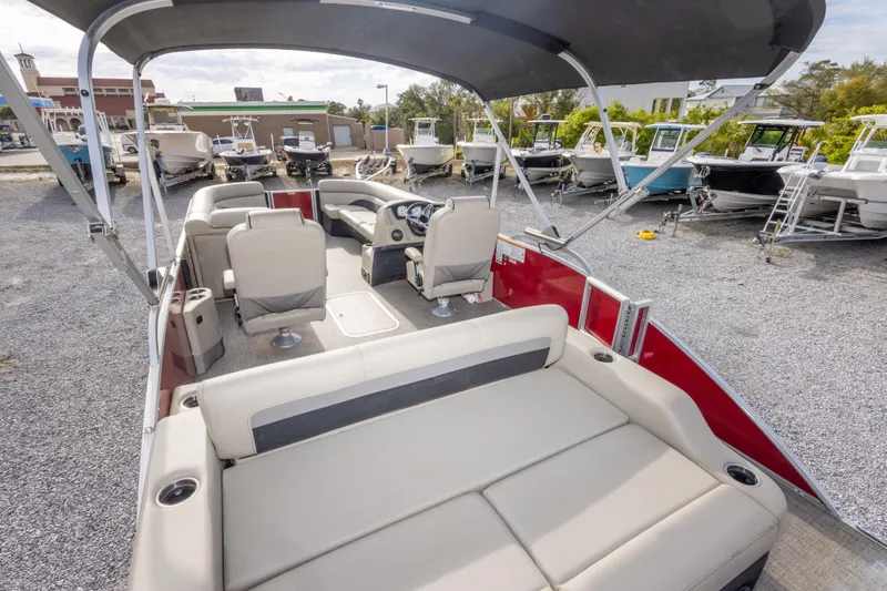 Slide: The Image of 2021 Barletta C24UC pontoon boat with spacious seating and canopy, parked in a marina. - 24