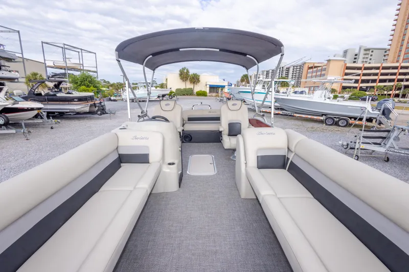 Slide: The Image of 2021 Barletta C24UC pontoon boat with spacious seating and canopy in a marina setting. - 32