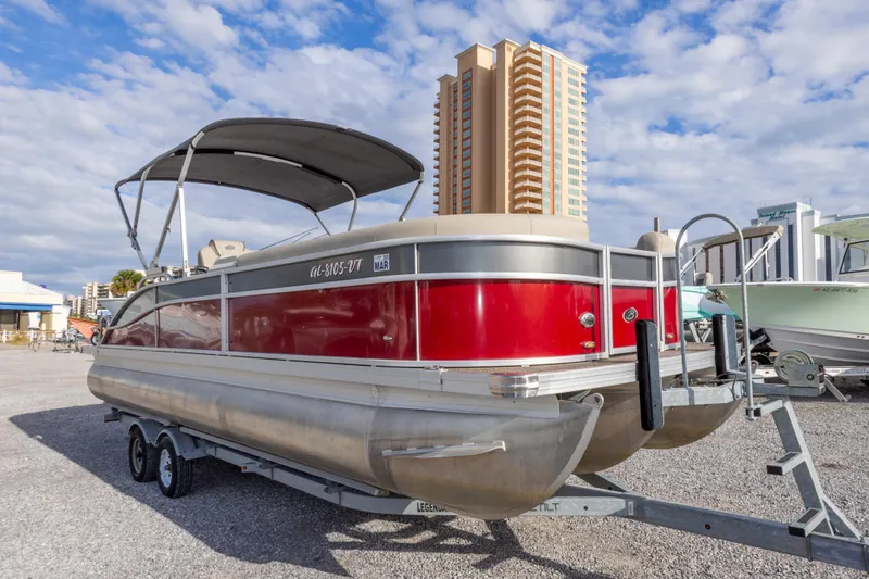 Slide: The Image of 2021 Barletta C24UC pontoon boat on trailer, red exterior, cityscape background. - 6