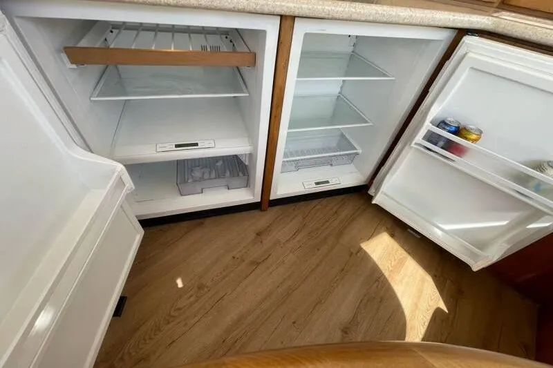 Slide: The Image of Open refrigerator in 2000 Silverton 453 Motor Yacht, showcasing spacious interior and wooden flooring. - 24