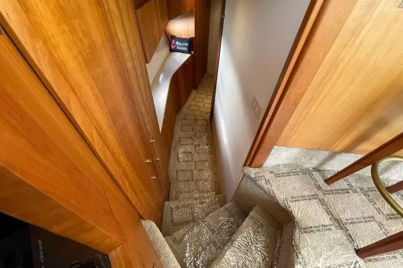Slide: The Image of Interior view of 2000 Silverton 453 Motor Yacht, featuring carpeted stairs and wooden cabinetry. - 32