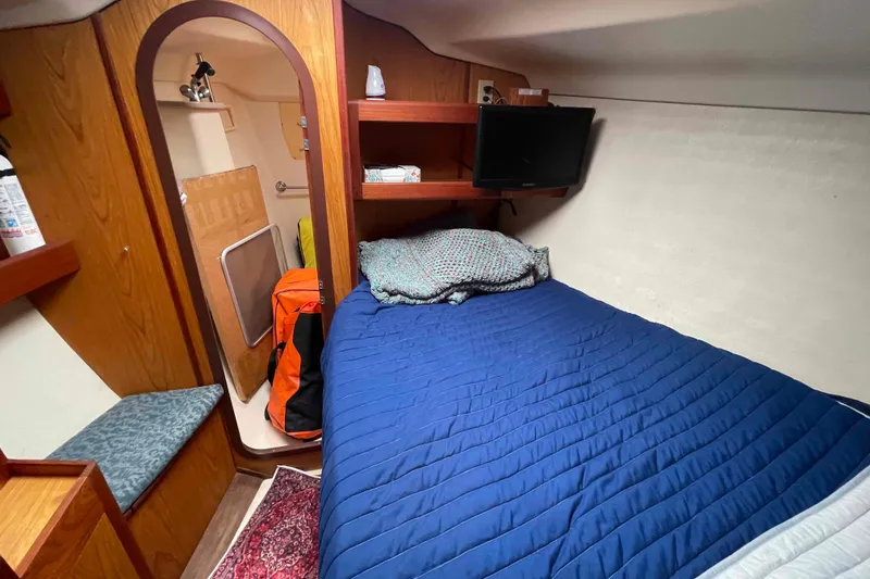 Slide: The Image of Cozy cabin interior of 2000 Hunter 410 sailboat with bed, TV, and storage. - 36