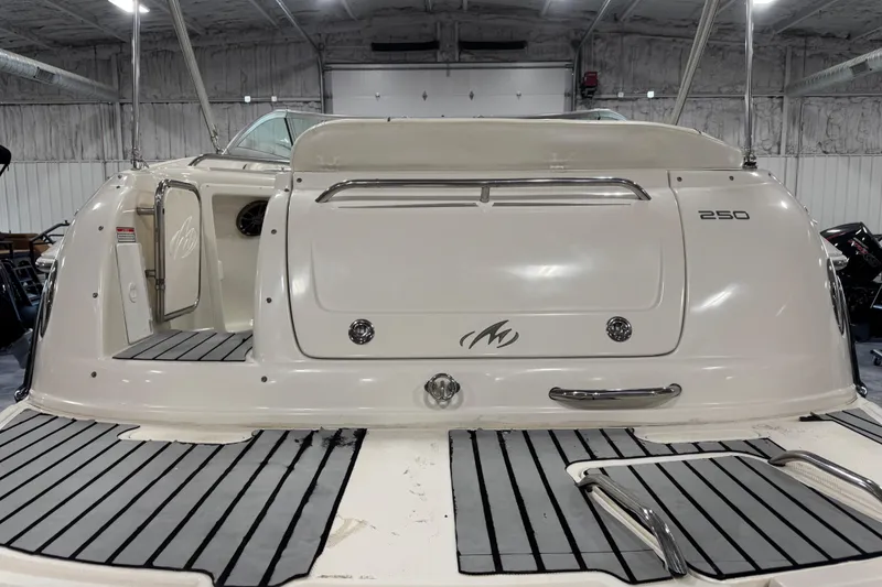 Slide: The Image of 2005 Monterey 250 Cruiser boat stern view in a garage, featuring sleek design and swim platform. - 5