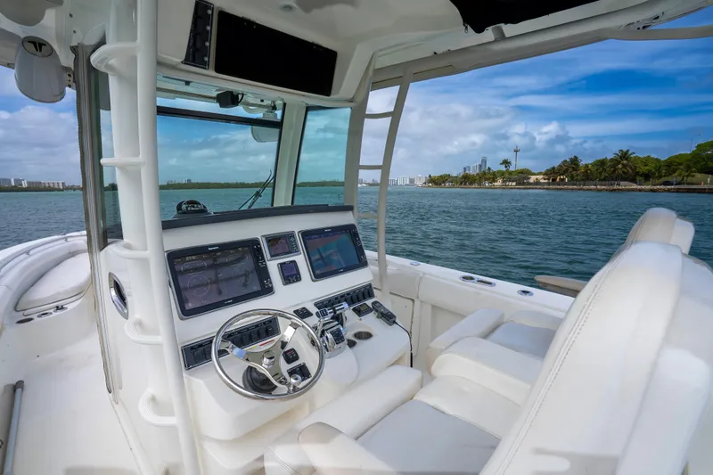 Slide: The Image of 2013 Boston Whaler 320 Outrage helm with modern controls, cruising on a scenic waterway. - 13