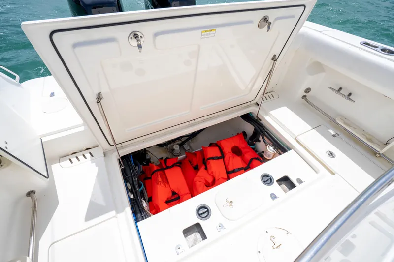 Slide: The Image of Open storage compartment on 2013 Boston Whaler 320 Outrage with life jackets inside. - 18