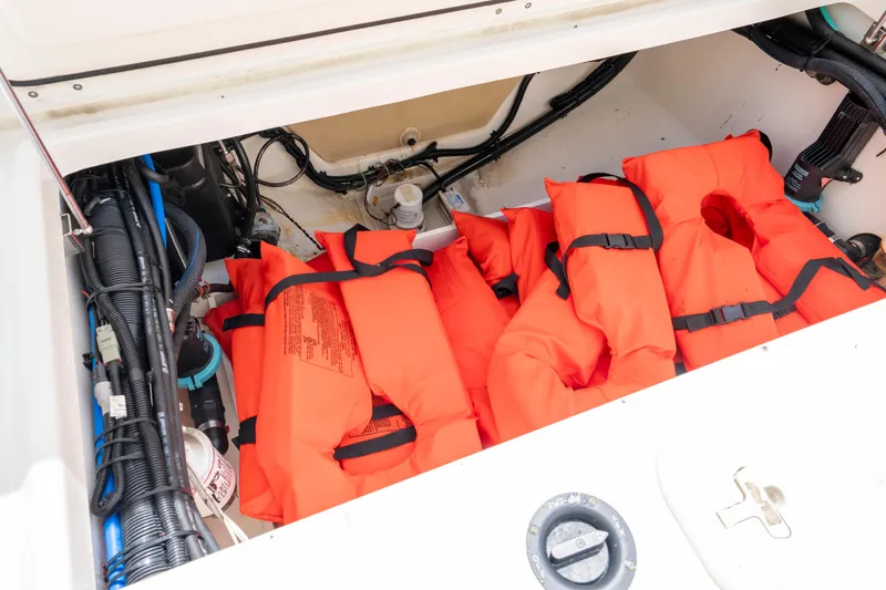 Slide: The Image of Storage compartment with orange life jackets on a 2013 Boston Whaler 320 Outrage boat. - 19