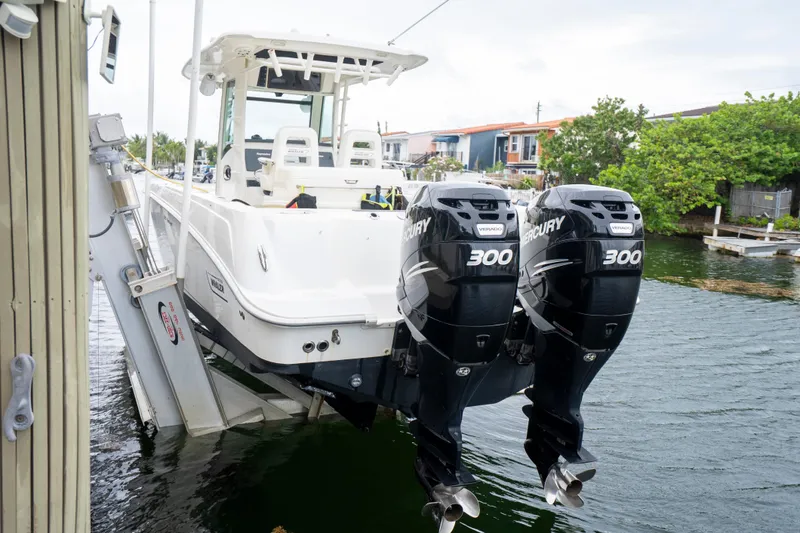 Slide: The Image of 2013 Boston Whaler 320 Outrage with twin Mercury 300 engines docked by waterfront homes. - 6