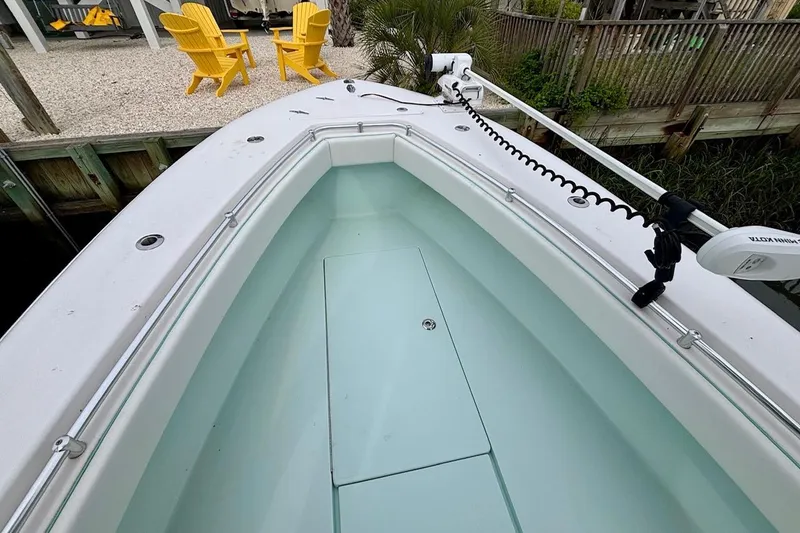 Slide: The Image of 2018 Contender 25 Tournament boat bow with trolling motor, docked near yellow chairs. - 12