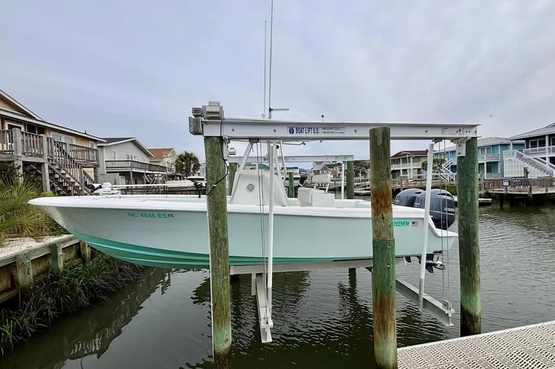 Slide: The Image of 2018 Contender 25 Tournament boat on lift at dockside, surrounded by waterfront homes. - 5