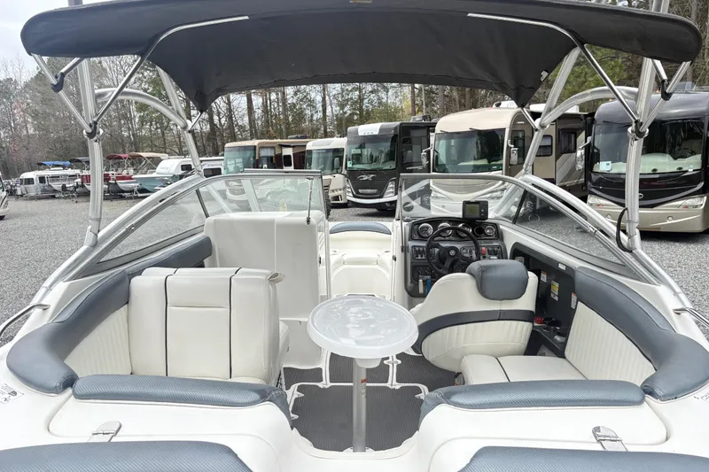 Slide: The Image of 2007 Yamaha AR230 boat interior with seating, table, and dashboard, parked near RVs. - 8
