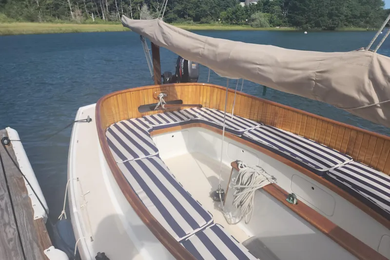 Slide: The Image of 1978 Marshall Sanderling sailboat with striped cushions docked on a serene lake. - 4