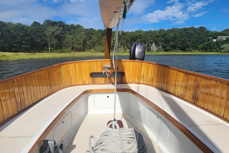 Slide: The Image of 1978 Marshall Sanderling sailboat with wooden interior, moored on a scenic lake under a blue sky. - 5