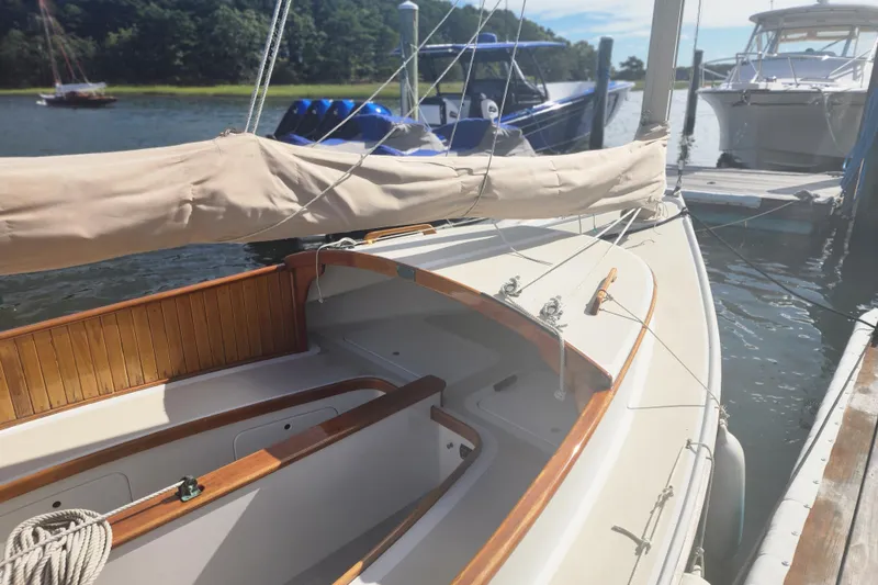 Slide: The Image of 1978 Marshall Sanderling sailboat docked, featuring wooden trim and covered sail, in a serene marina setting. - 7