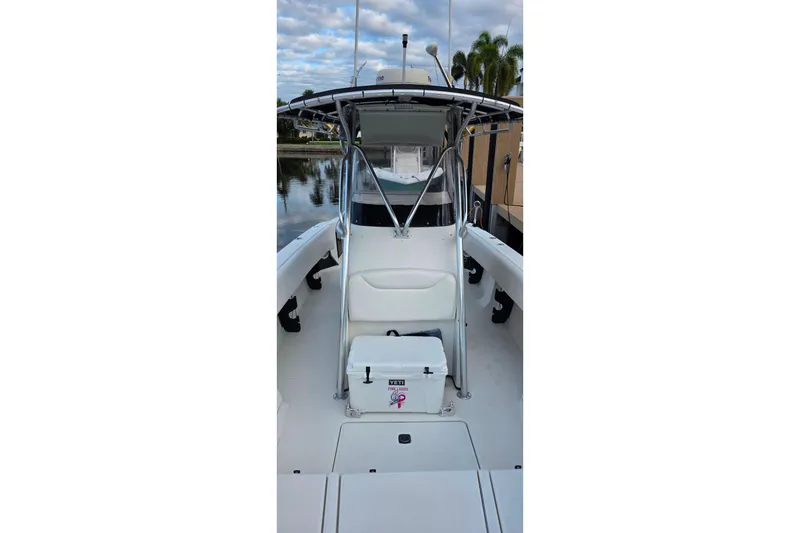 Slide: The Image of 1999 Hydra-Sports 3000 CC boat interior with seating and cooler, docked by calm water. - 16