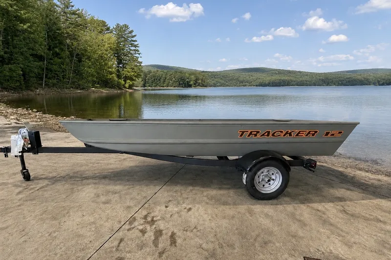 The Image of 2026 Tracker Grizzly 12 Jon boat on trailer by a scenic lake. - 0