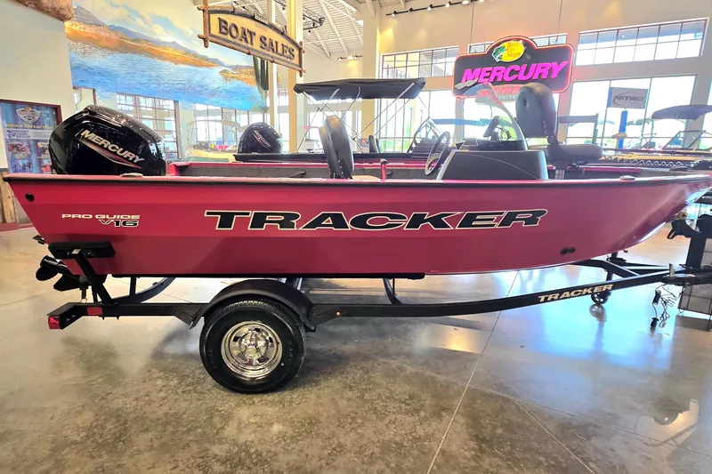 Slide: The Image of 2026 Tracker Pro Guide V-16 SC boat displayed in showroom with Mercury engine. - 6