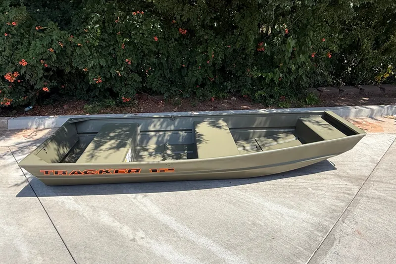 Slide: The Image of 2026 Tracker Grizzly 12 Jon boat on pavement, surrounded by greenery. - 4
