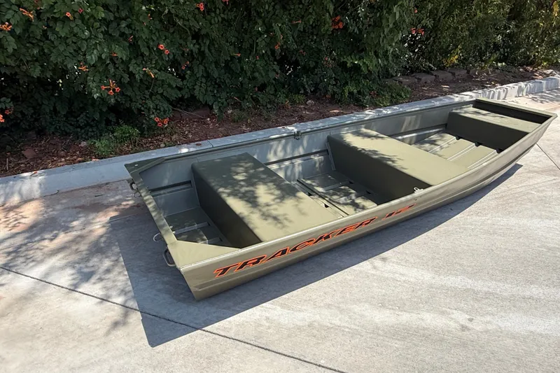 Slide: The Image of 2026 Tracker Grizzly 12 Jon boat on pavement, surrounded by greenery. - 6