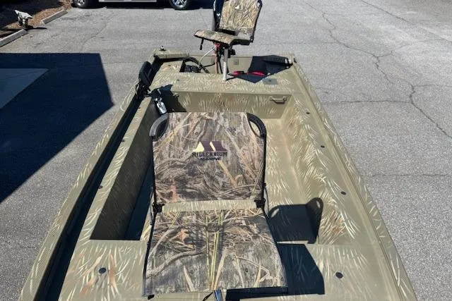 Slide: The Image of 2024 Tracker Grizzly 1754 MVX Jon boat with camouflage seating on pavement. - 10