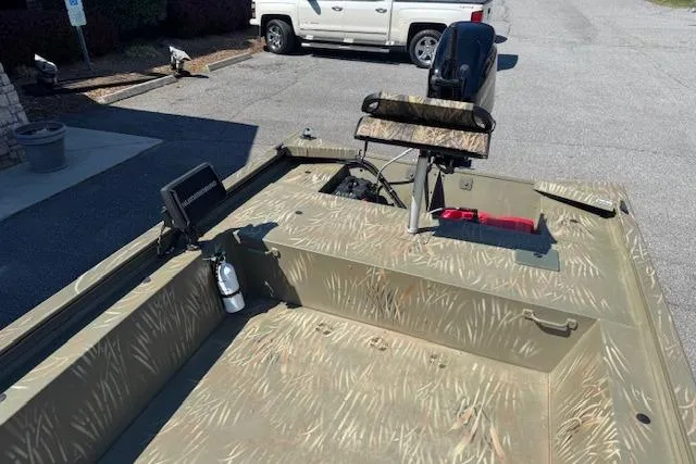 Slide: The Image of 2024 Tracker Grizzly 1754 MVX Jon boat with camouflage design in a parking lot. - 11
