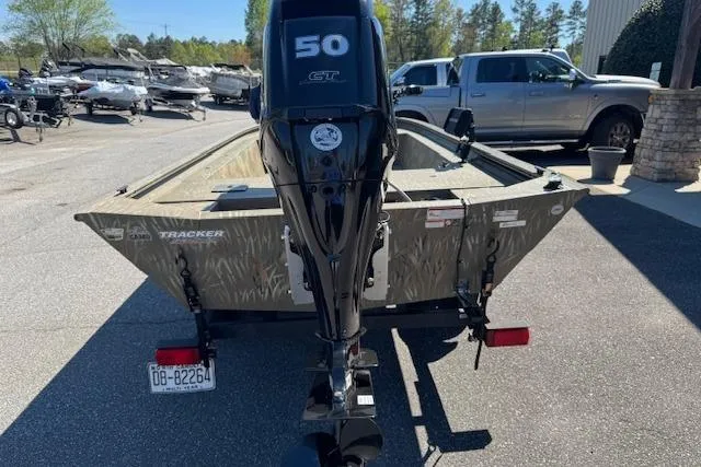 Slide: The Image of 2024 Tracker Grizzly 1754 MVX Jon boat with 50 HP motor, parked outdoors. - 5