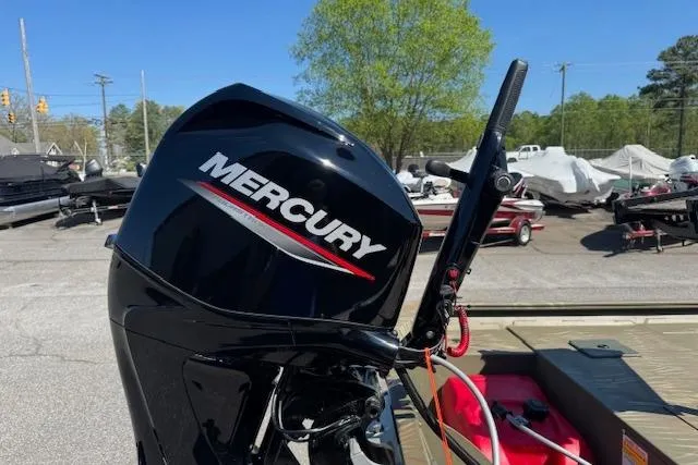 Slide: The Image of 2024 Tracker Grizzly 1754 MVX Jon boat with Mercury outboard motor in a marina setting. - 6