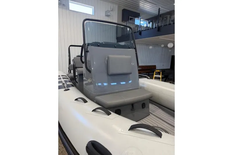 Slide: The Image of 2023 Brig Navigator 610 inflatable boat in showroom, featuring sleek design and modern seating. - 5