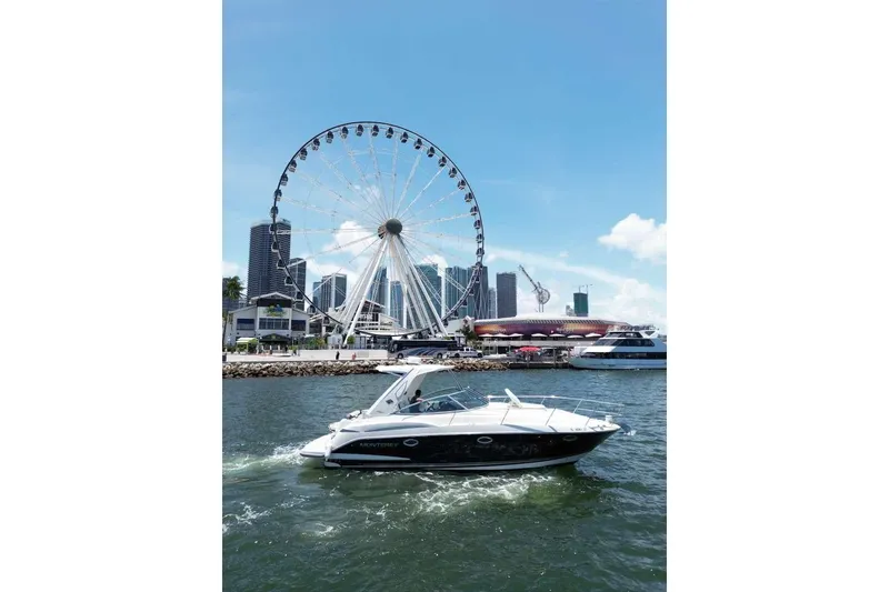 Slide: The Image of 2014 Monterey 320 Sport Yacht cruising near a Ferris wheel and city skyline. - 11