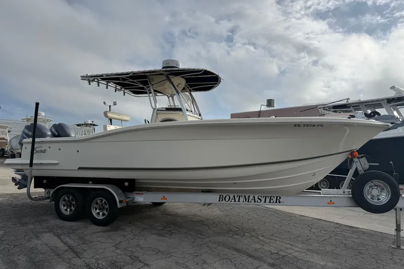 Slide: The Image of 2006 Scout 260 Sportfish boat on a trailer, parked outdoors under a cloudy sky. - 28