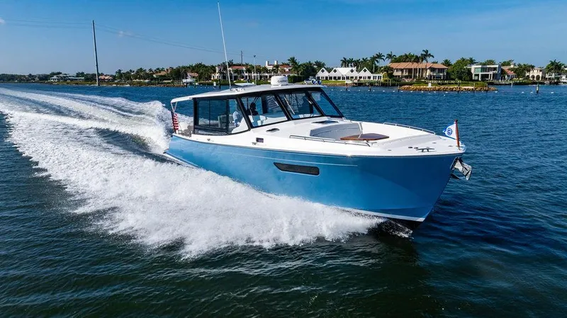 The Image of 2024 MJM 4 boat cruising on a sunny day, with waterfront homes in the background. - 0