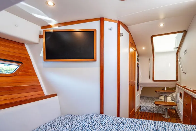 Slide: The Image of 2024 MJM 4 yacht interior with wood accents, TV, and cozy seating area. - 15