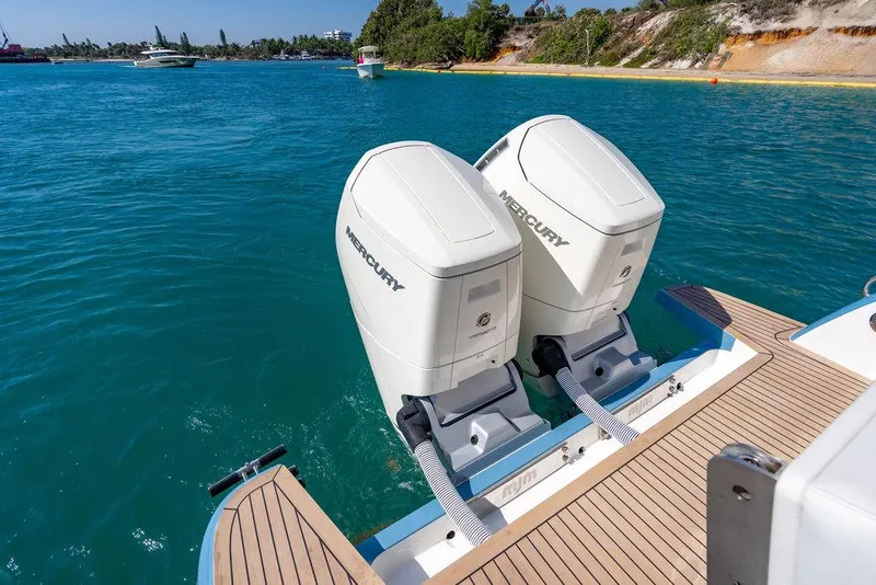 Slide: The Image of Twin Mercury outboard engines on a 2024 MJM 4 boat, cruising in clear blue waters. - 25
