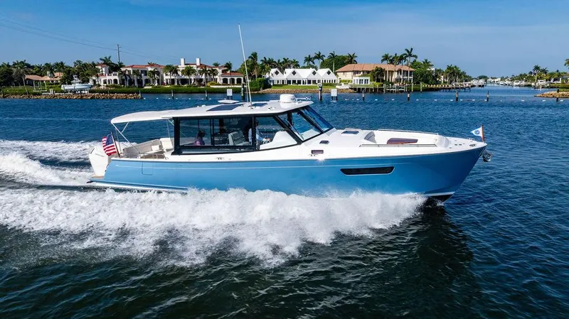 Slide: The Image of 2024 MJM 4 boat cruising on a sunny day near waterfront homes. - 3