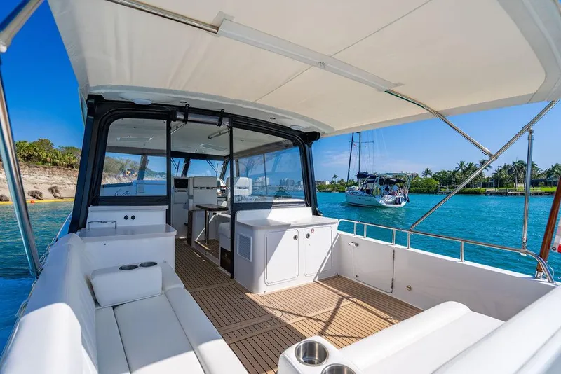 Slide: The Image of 2024 MJM 4 yacht interior with white seating, open deck, and scenic ocean view. - 4