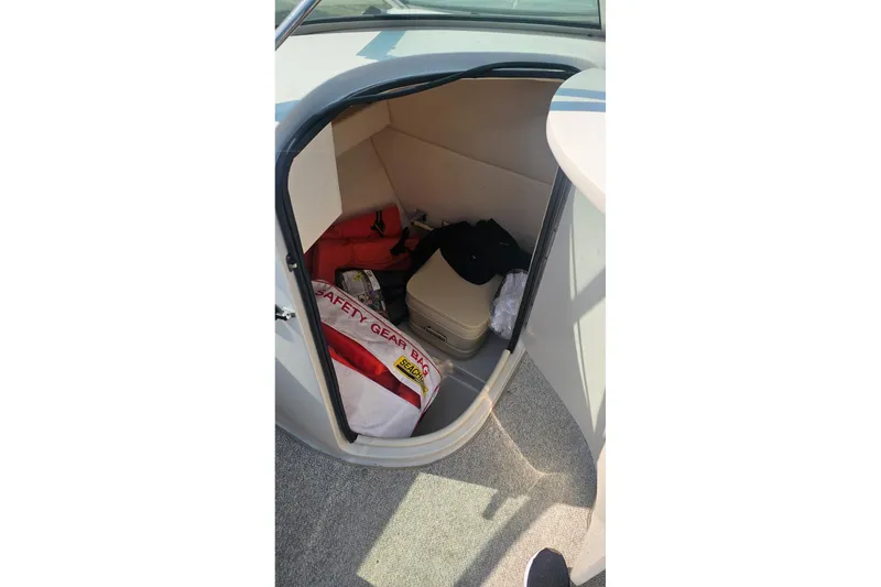 Slide: The Image of Storage compartment in a 2003 Sea Ray 220 Sundeck with safety gear and equipment. - 13