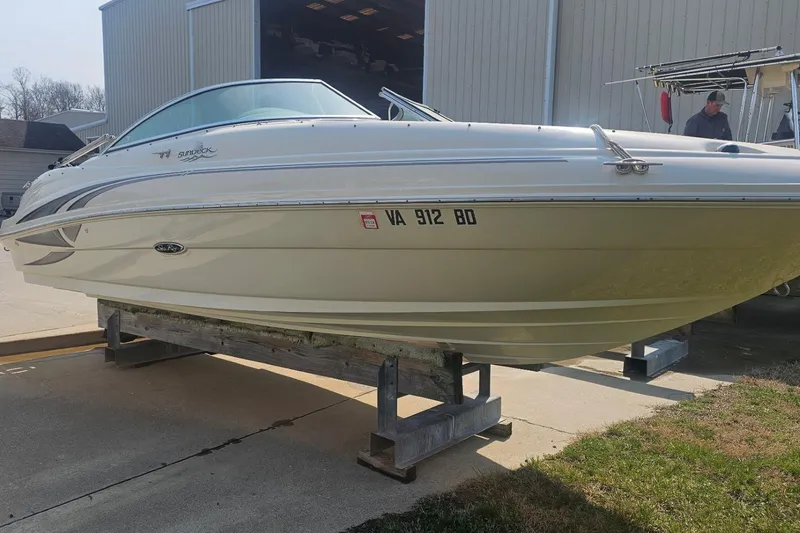 The Image of 2003 Sea Ray 220 Sundeck boat on a trailer, parked outside a building. - 4