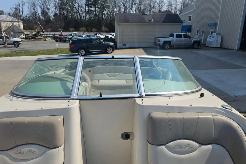 Slide: The Image of 2003 Sea Ray 220 Sundeck boat interior with windshield and seating, parked outdoors. - 8