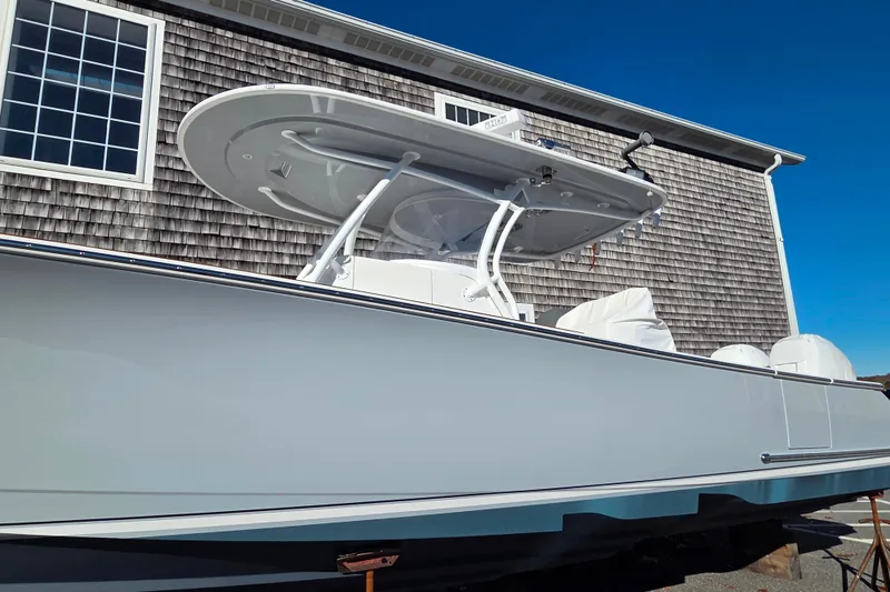 Slide: The Image of 2022 Valhalla Boatworks V-33, sleek design, parked near a wooden building under clear blue sky. - 3