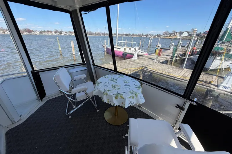 Slide: The Image of 1997 Carver 400 Cockpit Motor Yacht interior with chairs and table, overlooking marina. - 13