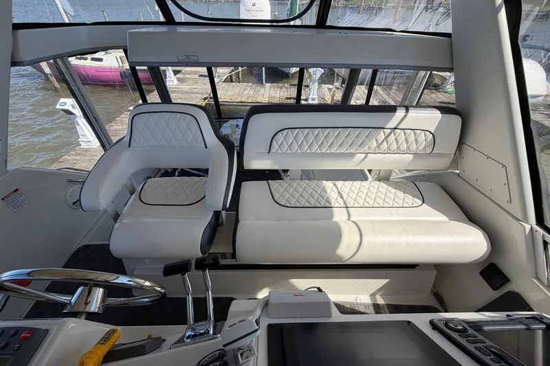 Slide: The Image of Interior of 1997 Carver 400 Cockpit Motor Yacht with white seating and steering controls. - 21