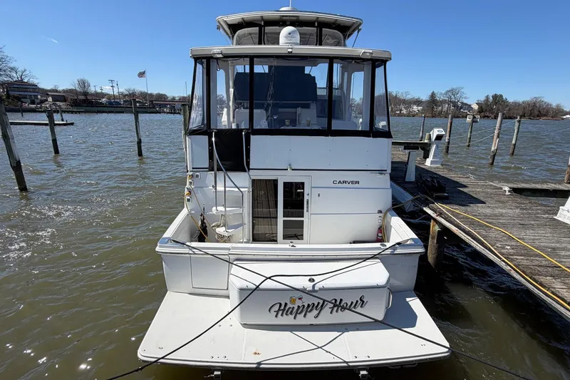 Slide: The Image of 1997 Carver 400 Cockpit Motor Yacht docked, rear view with "Happy Hour" nameplate. - 3