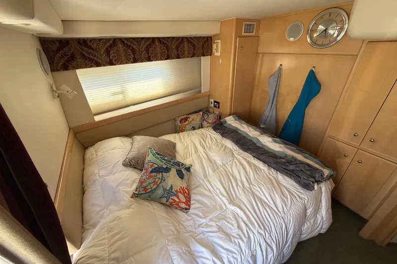 Slide: The Image of Cozy bedroom in a 1997 Carver 400 Cockpit Motor Yacht with decorative pillows and wooden cabinetry. - 42