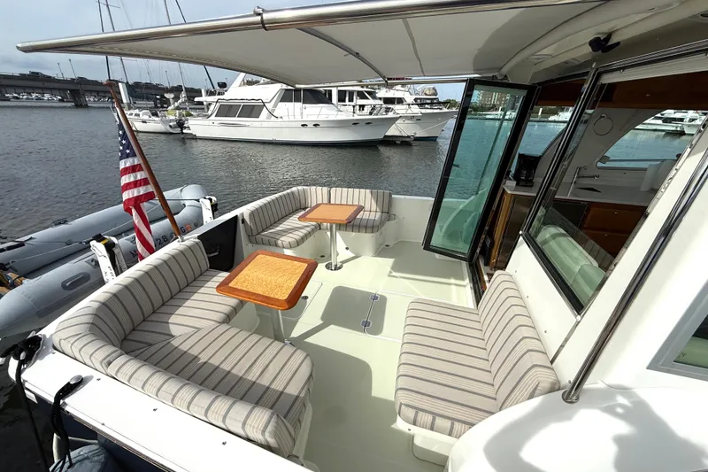 Slide: The Image of 2018 Back Cove 41 yacht with striped seating, wooden tables, and marina view. - 2